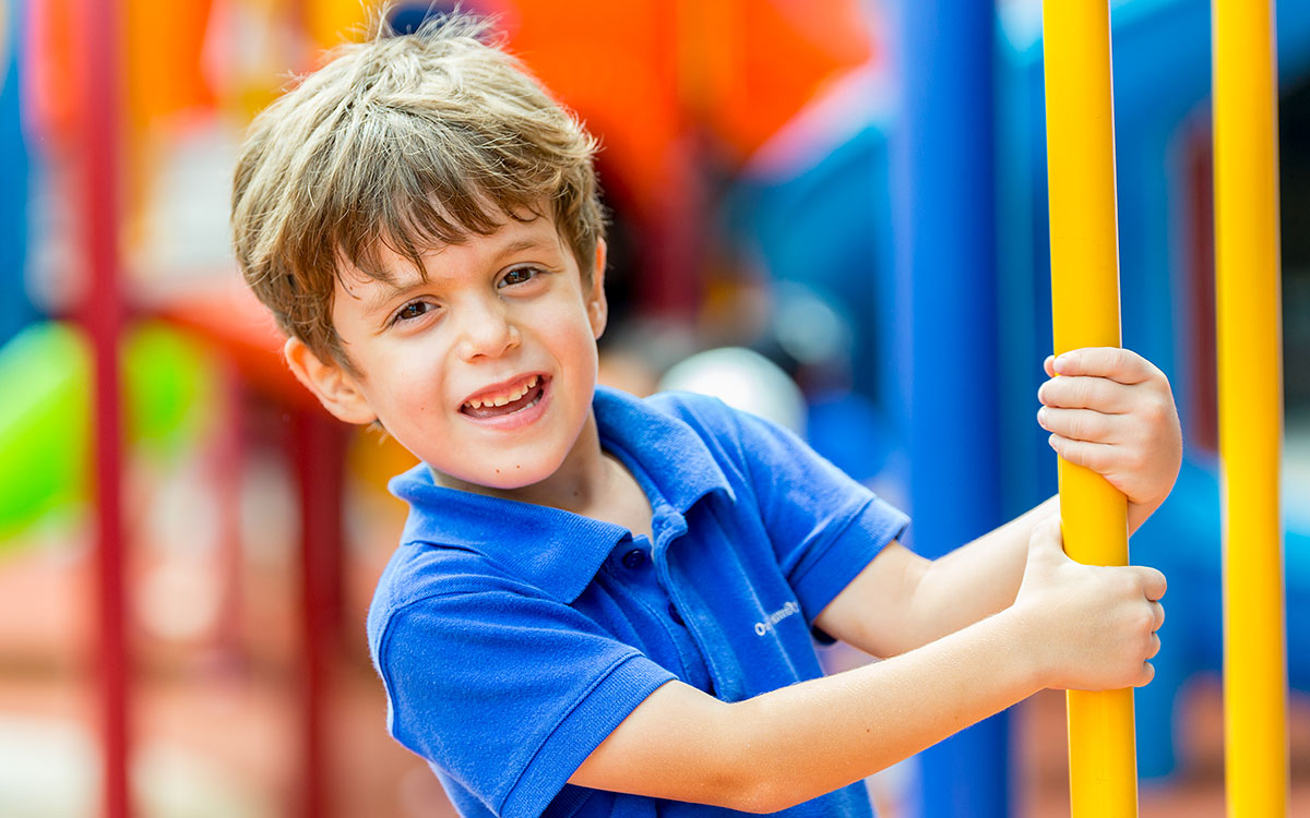 A male OFS Kindergarten student standing in the playground