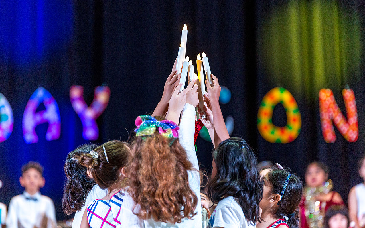 OFS Elementary School students holding candles on the stage during UN Concert Day