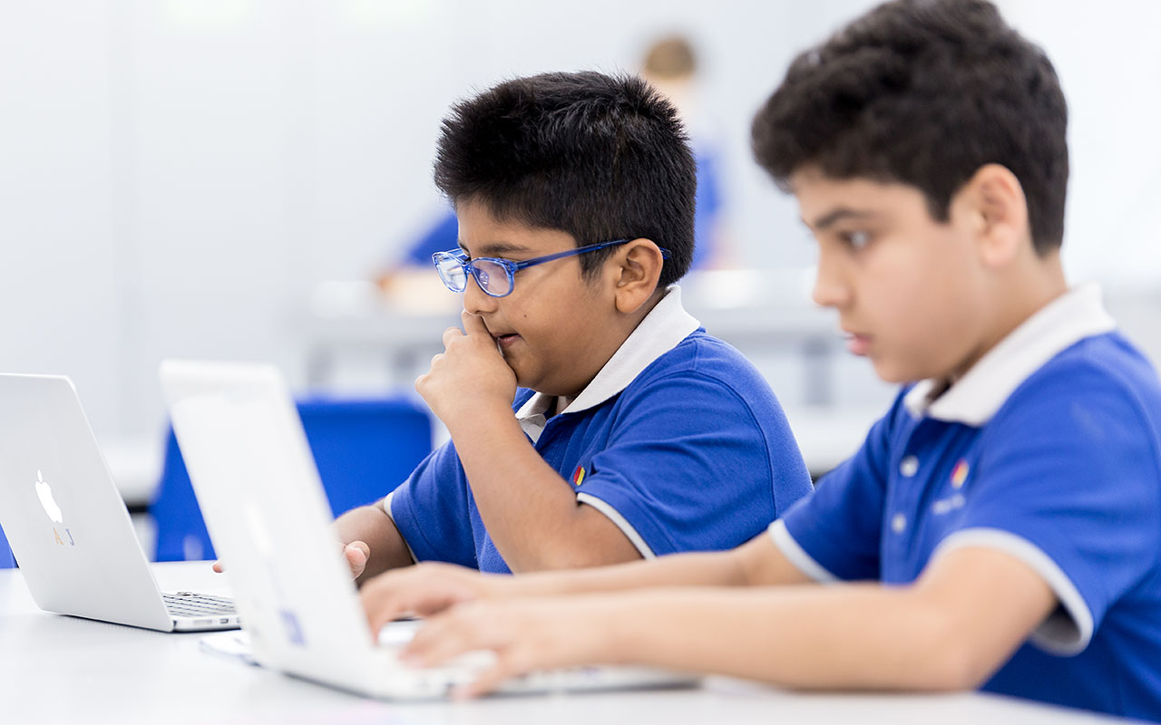 Two OFS Middle School students typing on a Apple MacBook Pro laptops during math coding or computer application lesson