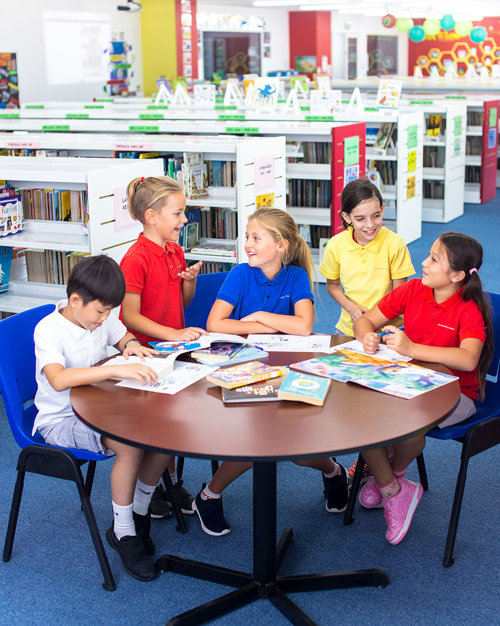 Five OFS Elementary School conversing around a round table inside the Elementary School library
