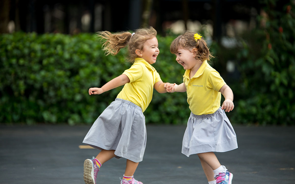 Two female OFS Kindergarten students playing on the OFS garden